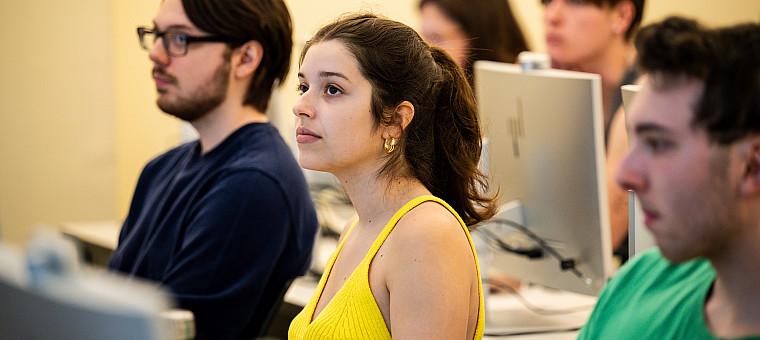 学生s sit in front of computers in a classroom.